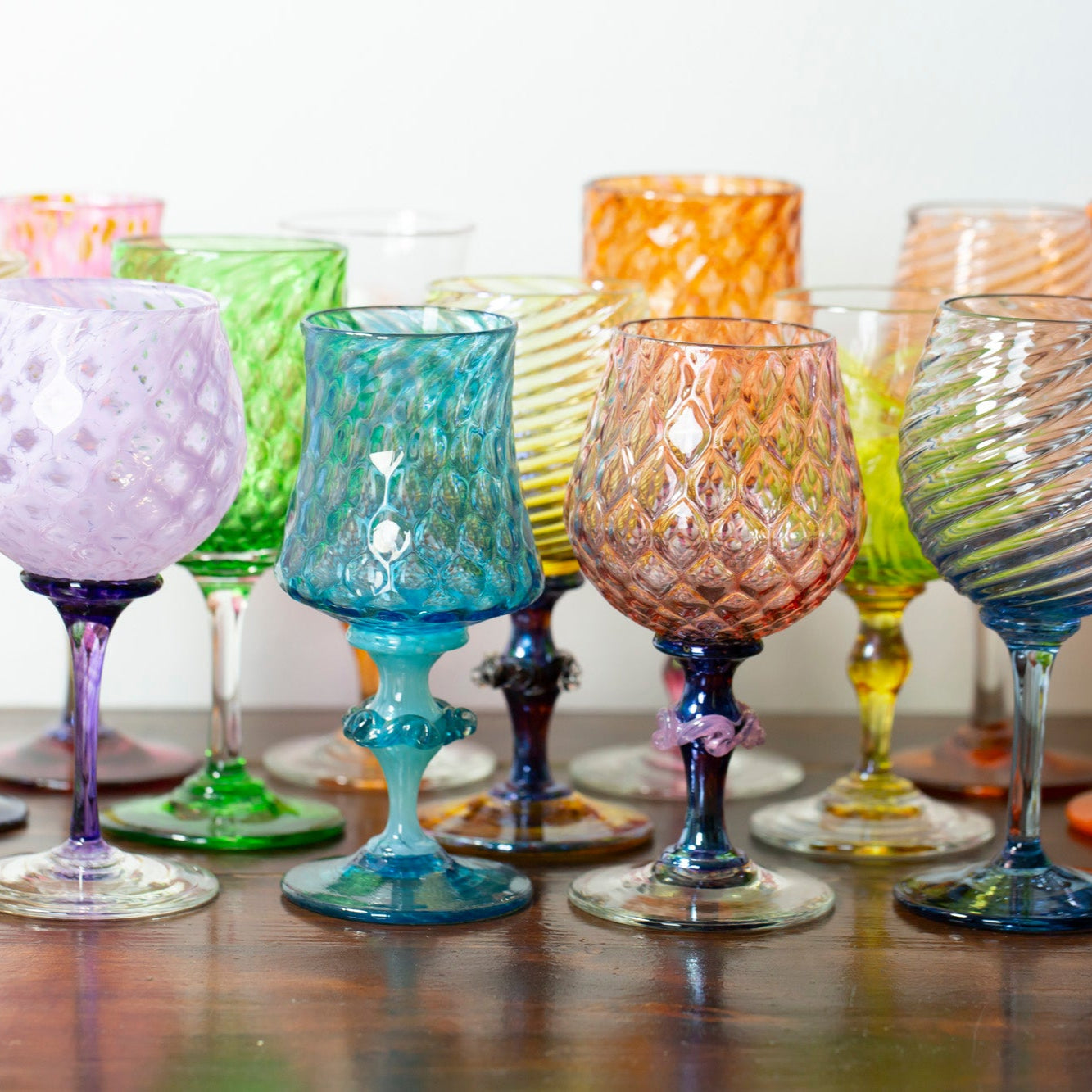 Collection of colorful glass goblets on a wooden surface