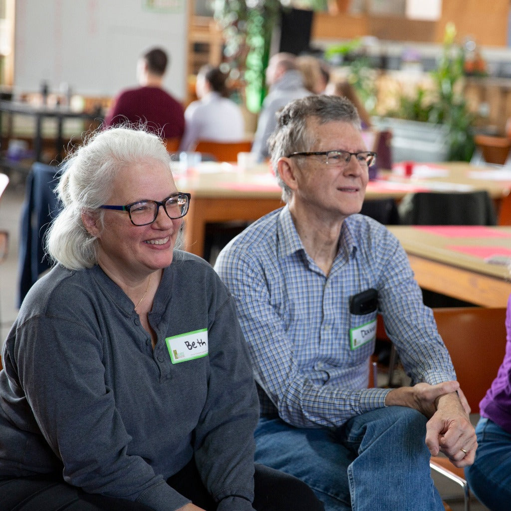 Two Glass Heart class students smile while watching their glassblower's safety demonstration.