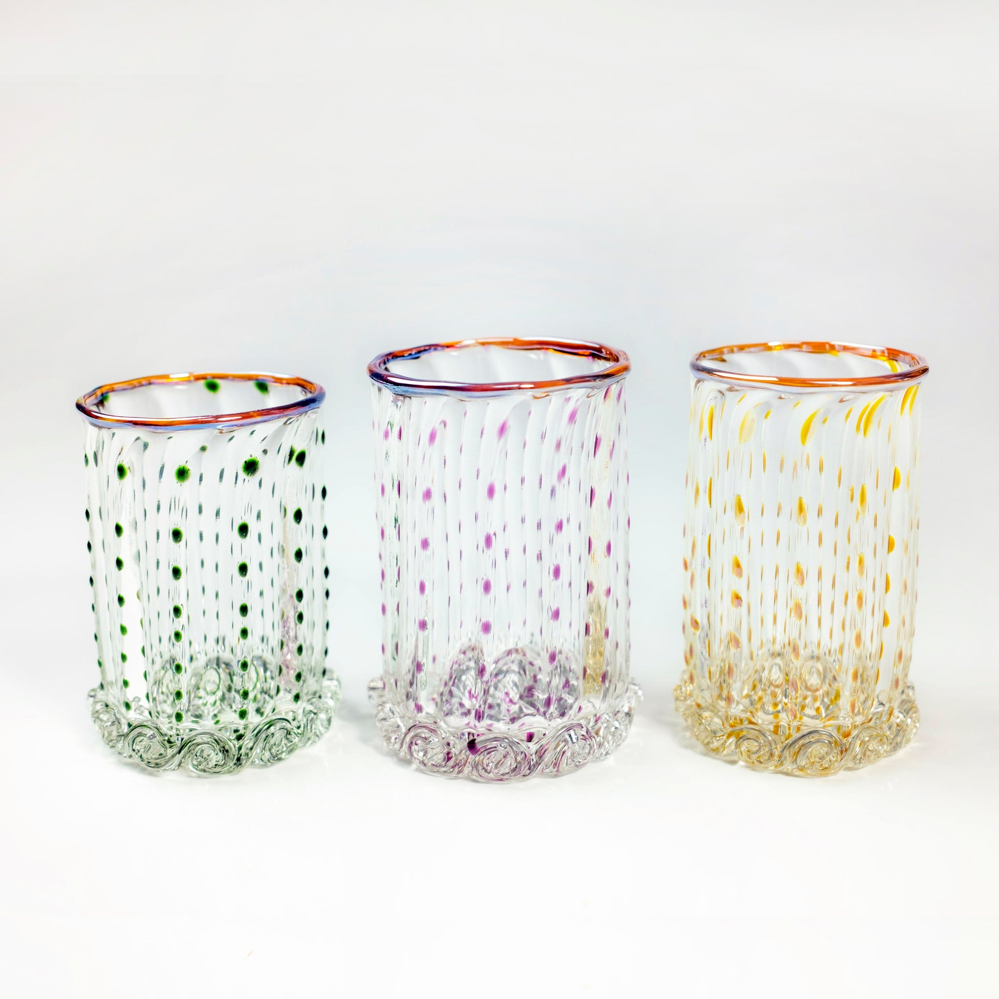 Three colorful glass tumblers with decorative patterns on a white background