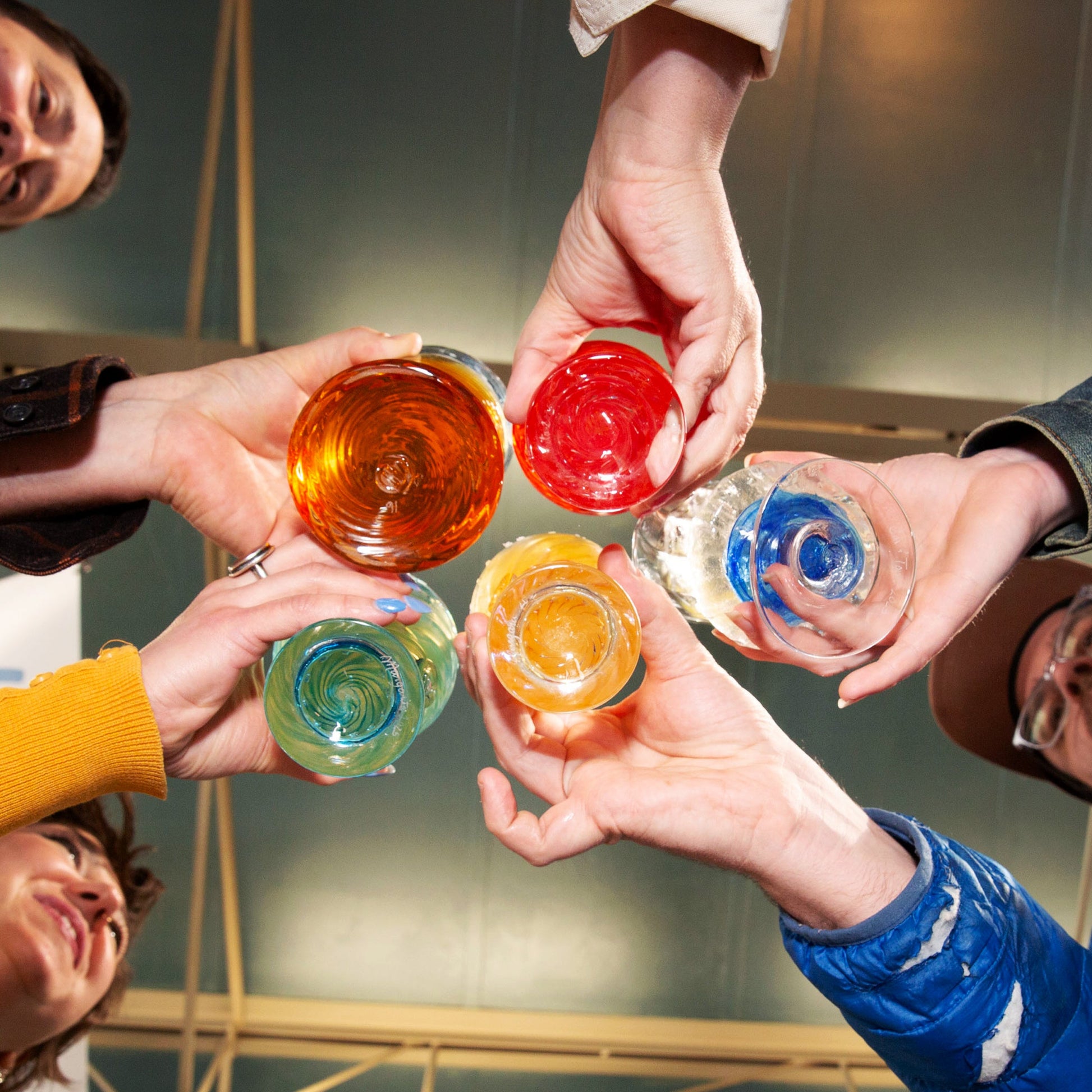 People holding colorful glasses in a celebratory gesture.