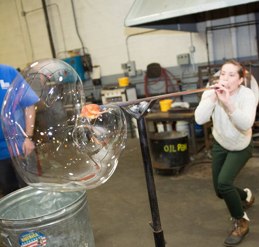 Big Bubble Blow student blows a bubble of molten glass.