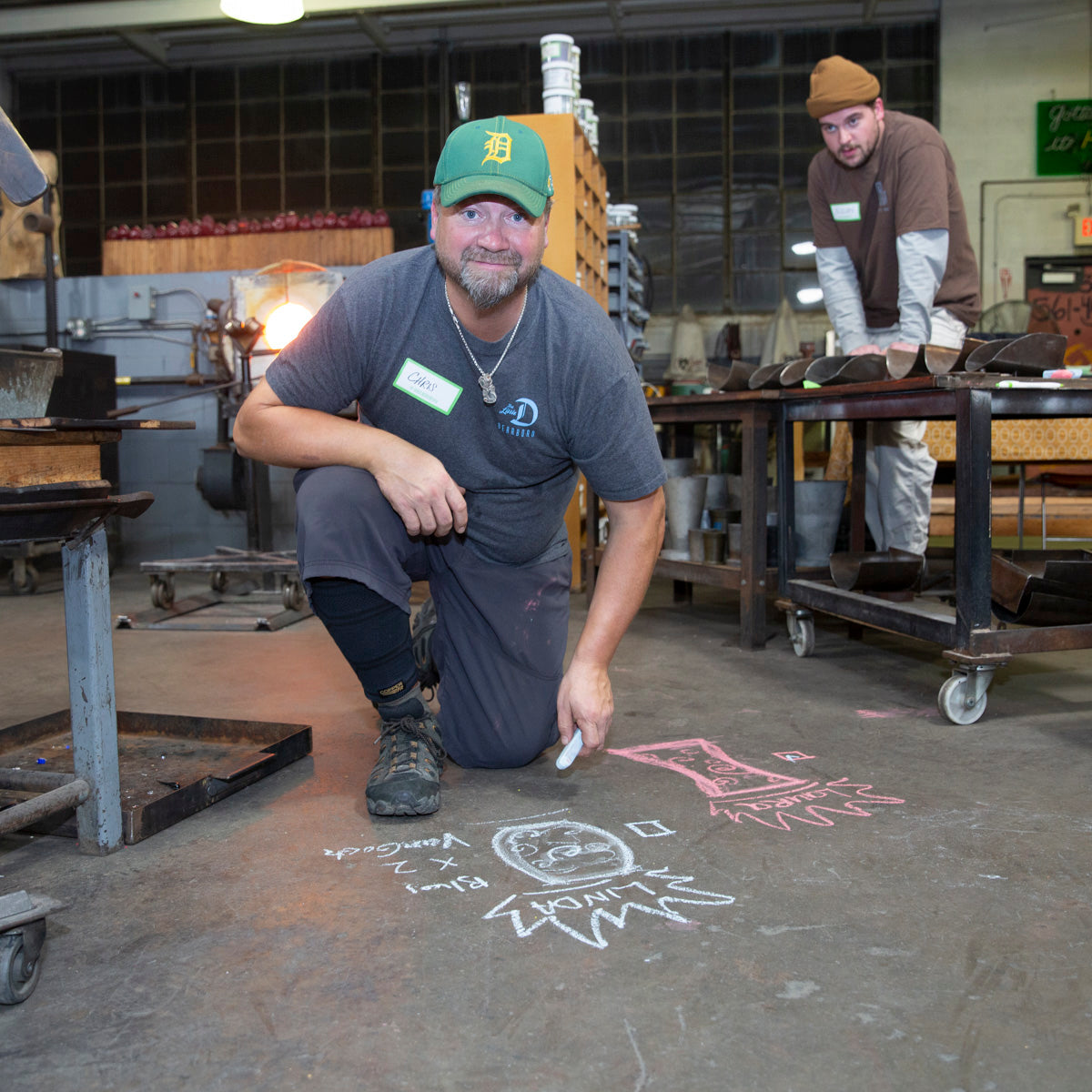 Chris, the co-founder and co-owner of the Glass Academy, draws on the cement floor with chalk to help a Happy Hour class participant to design their custom drinkware.