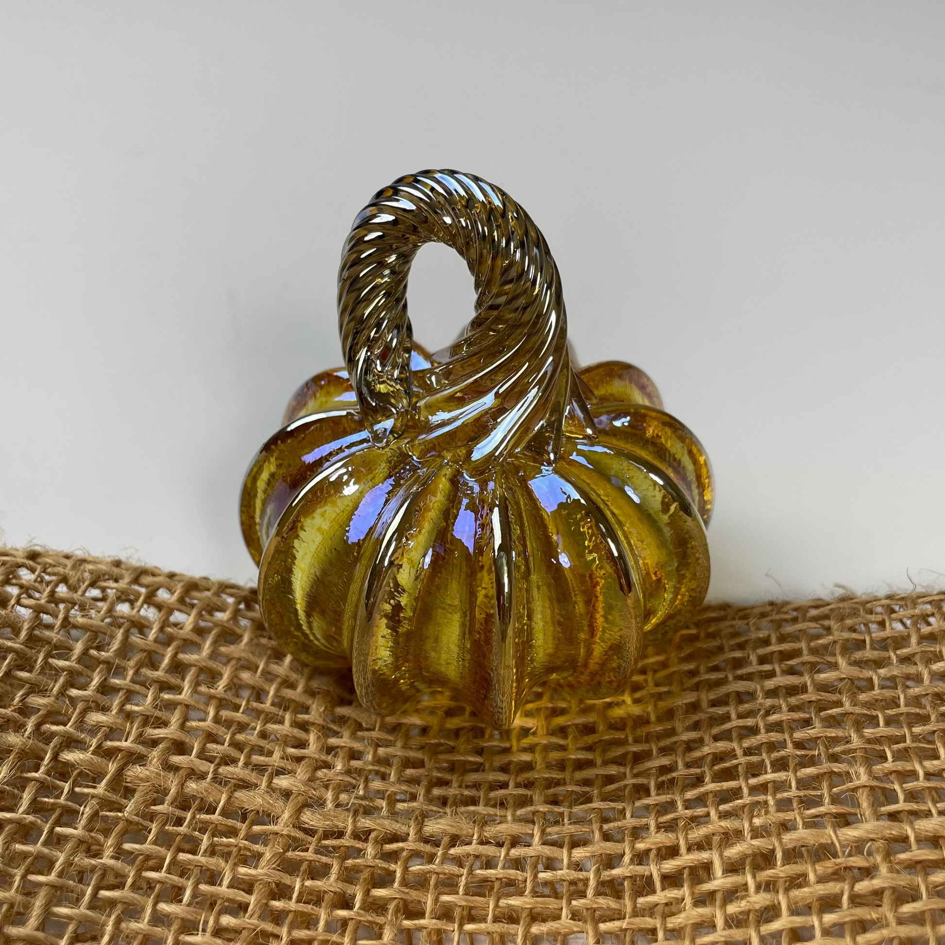 Decorative glass pumpkin with a handle on a burlap surface