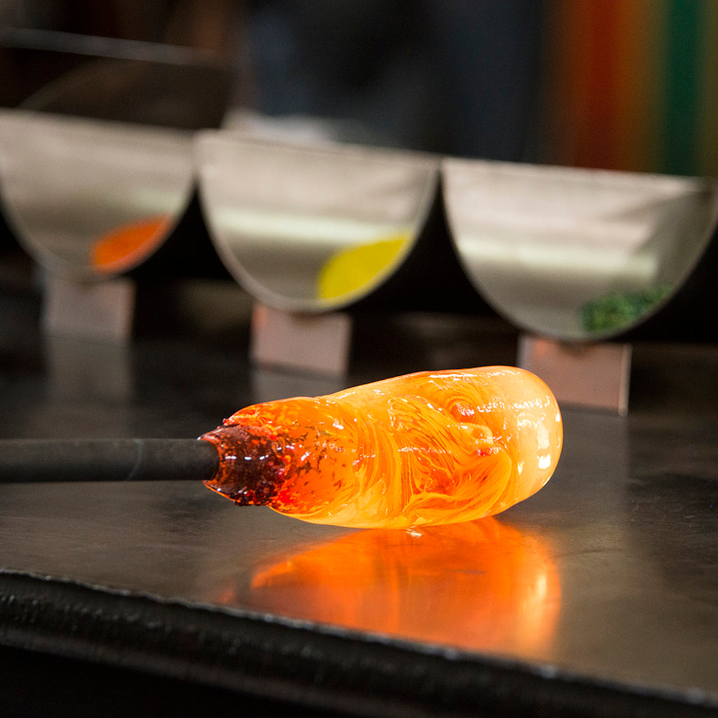 A gather of molten glass is rolled and shaped on the marver.