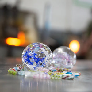 A shot of two Meditation Globes sounded by colorful glass twisties. Sign up for one of our glass blowing classes today and make your own glass paperweight at the Glass Academy!